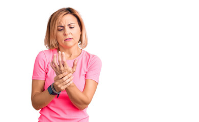 Young blonde woman wearing sportswear suffering pain on hands and fingers, arthritis inflammation