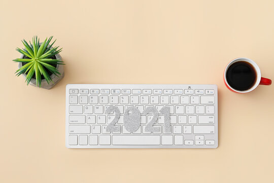 Computer keyboard with figure 2021 and coffee on color background - Powered by Adobe
