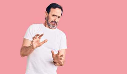 Middle age handsome man wearing casual t-shirt disgusted expression, displeased and fearful doing...