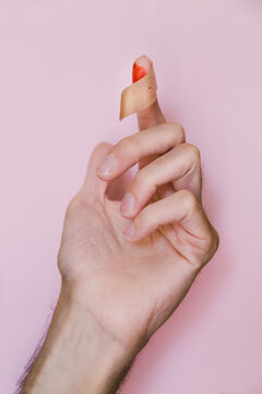 Bloody finger with patch on pink background