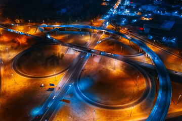 Urban transportation concept. Road highways and junctions at night with car and truck traffic, aerial view from drone.