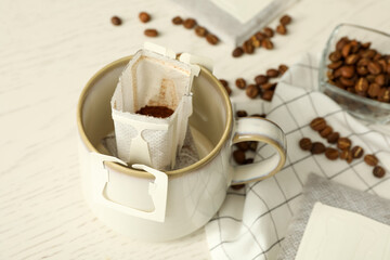 Drip coffee bag in cup on white table, closeup