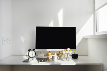 Blank screen desktop computer in modern minimal office room with autumn decorations. Paper boxes in a trolley on desktop. Online shopping concept