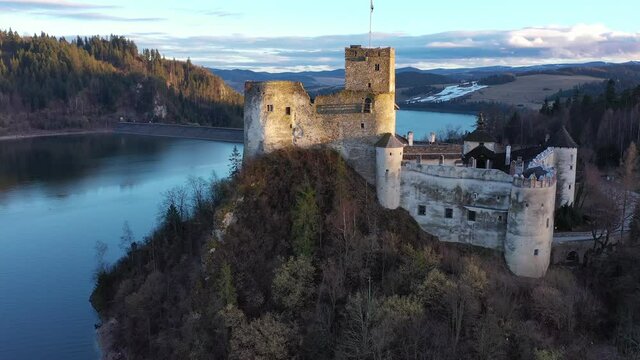 Scenic view of ancient fortified Dunajec Castle on top of hill above Czorsztyn lake in Polish city of Niedzica at dusk