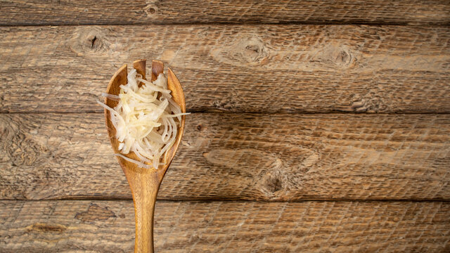 sauerkraut (fermented cabbage) on a wooden spoon against rustic barn wood background, probiotics concept - fermented food good for gut health