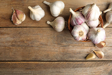Fresh organic garlic on wooden table, flat lay. Space for text