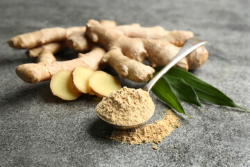 Dry ginger powder, fresh root and leaves on grey table