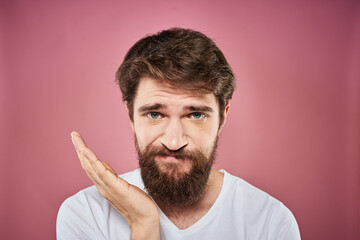 bearded man in white t-shirt emotions displeased facial expression studio pink background