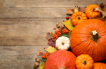 Flat lay composition with pumpkins and autumn leaves on wooden table. Space for text