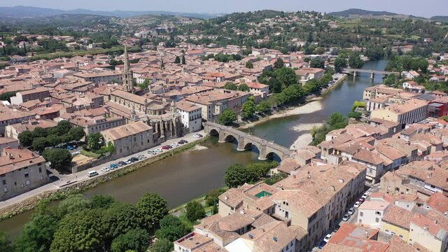 Scenic aerial view of French commune of Limoux on Aude River overlooking gothic spire of Church of Saint Martin in summer, Occitanie 