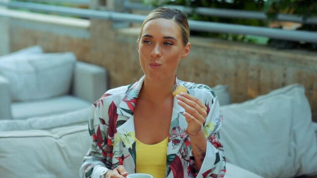 Stylishly Dressed Woman Is Sitting In Cafe Eating Cookie And Other Holding Coffee. Outdoor. Coffee Break.