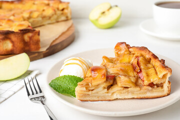 Slice of traditional apple pie with ice cream and mint on white table