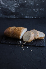 Sliced baguette on cutting board. Dark background