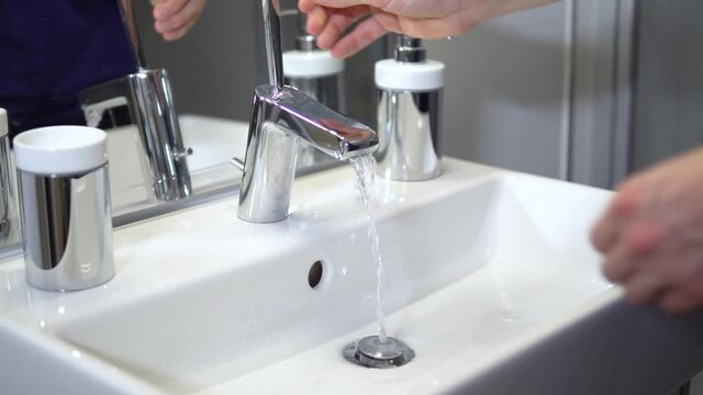 Slow-motion of white male washing hands with tab water in sterile bathroom. Person cares about hygiene.