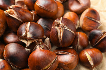 Tasty roasted edible chestnuts on parchment, closeup