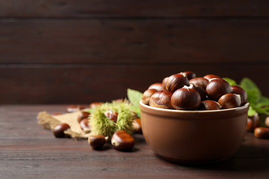 Fresh sweet edible chestnuts on brown wooden table. Space for text