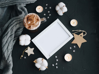 Blank photo frame, coffee, candles, cotton and a cozy gray sweater on a dark background