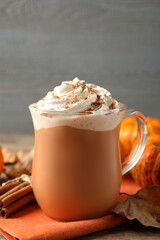Delicious pumpkin latte with whipped cream on table, closeup
