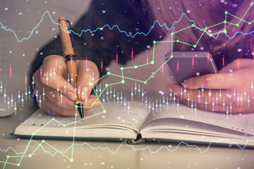 Double exposure of businesswoman hands typing on computer and forex graph hologram drawing....