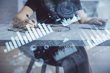 Double exposure of businesswoman hands typing on computer and forex chart hologram drawing. Financial analysis concept.