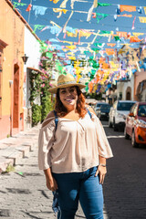 happy smiling young woman on summer city street mexico, curly hair with hat