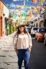 happy smiling young woman on summer city street mexico, curly hair with hat