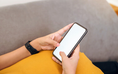 Hand holding a blank white screen smartphone on the sofa, for putting advertising to promote.