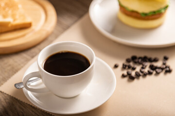 The hot black coffee cup in white glass and breakfast on the wooden table