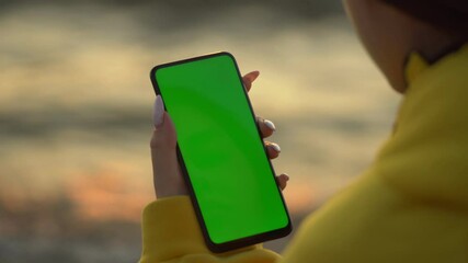 Handheld Camera: Point of View of Woman at beach Using Phone With Green Mock-up Screen Chroma Key Surfing Internet Watching Content Videos Blogs Tapping on Screen - Powered by Adobe