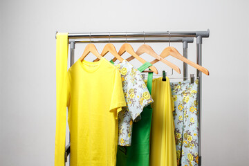 Bright yellow, green summer clothes hanging on the rail. Clothing for the holiday, relaxation at sea, summer walks.