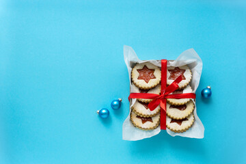 Traditional christmas linzer cookies with jam in gift box on blue background. Space for text