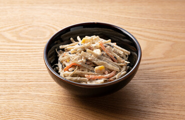 Burdock salad set against a wooden backdrop
