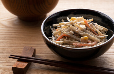 Burdock salad set against a wooden backdrop