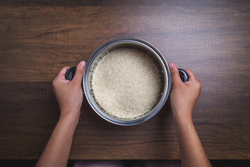 Jasmine rice in pot on wooden background.