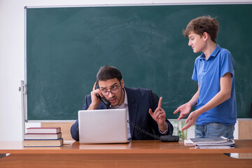 Young male teacher and schoolboy in the classroom