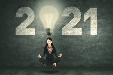 Businesswoman meditate with bulb and number 2021
