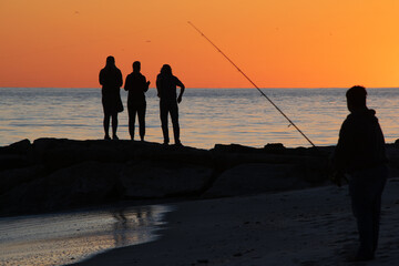 People and Fisherman at Sunset on Beach