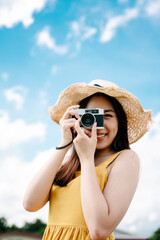 Fototapeta na wymiar Asian traveler woman taking photo with vintage film camera on bright sky background.