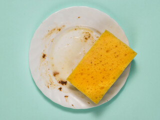 Sponge with detergent on a dirty plate on a blue background.