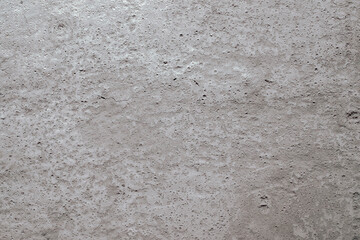 A close-up of a beige surface made of concrete, plaster, cement. Texture, background. Horizontal orientation, selective focus.