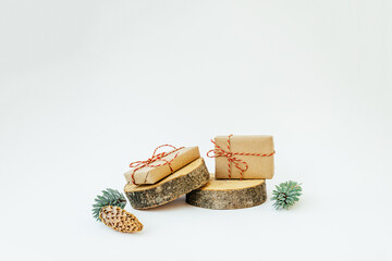 Two craft gifts on the wooden round cylinders shapes on the light background. Concept Christmas and New Year. Copy space.