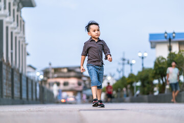 full length portrait of cute little asian boy walking on the street