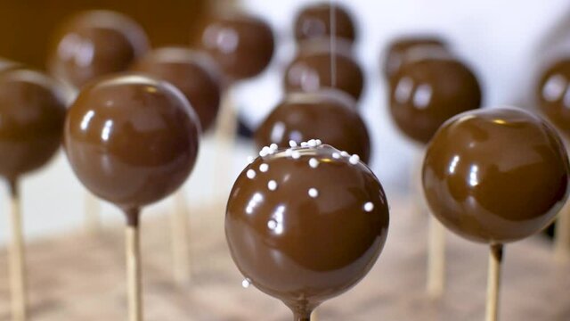 Dripping chocholate cakepops and decorating it with little white sprinkles.
