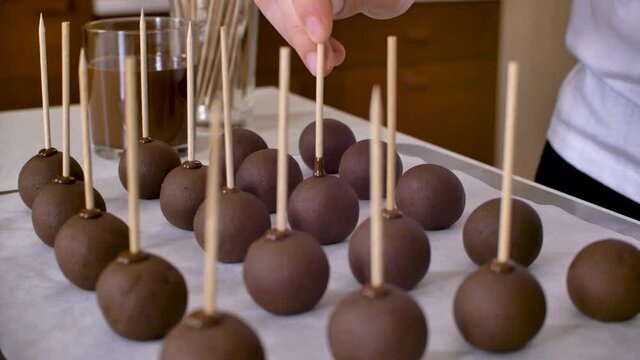 Assortment of plain cakepops, putting wooden stick in chocholate balls