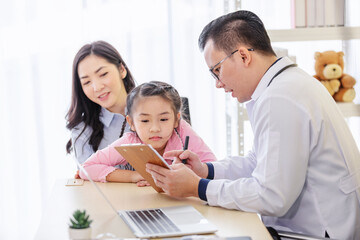 Pediatrician doctor describes the results of a physical examination to children and  mother holding baby in her hands.