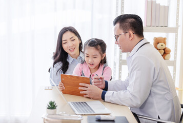 Pediatrician doctor describes the results of a physical examination to children and  mother holding baby in her hands.