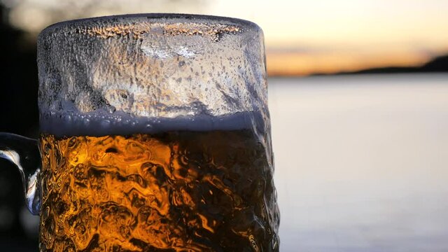 As the sun sets on the Swedish archipelago a cold lager beer is poured in to a rippled beer glass. Vibrant colors and great depth of field helps to enhance the stunning seaside setting.