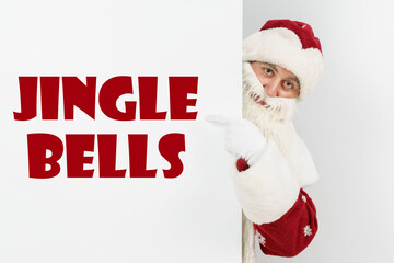 Santa Claus points his fingers at the board with the text - JINGLE BELLS