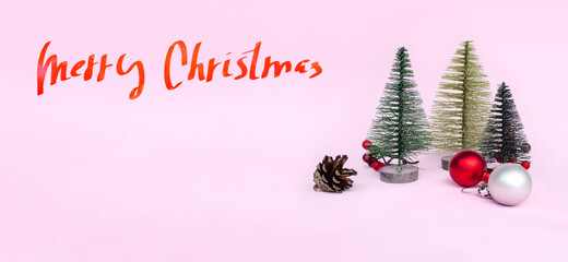 Merry Christmas word on pink holiday festive background. Christmas tree, pine cone, red balls at blur bokeh light background