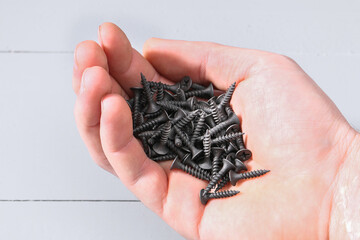 Black iron screws in the palm for wood. Fasteners, hardware in hand.